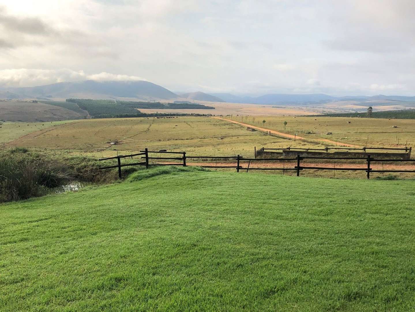 Ein Feld mit einem Zaun und Bergen im Hintergrund