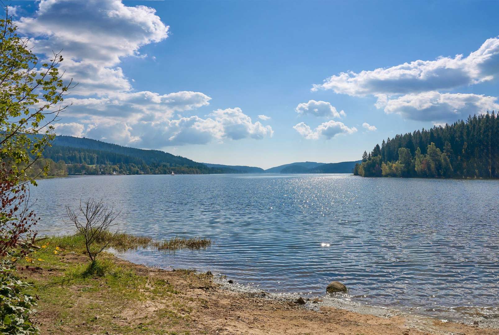 Ein See mit Bergen im Hintergrund und einem blauen Himmel mit Wolken