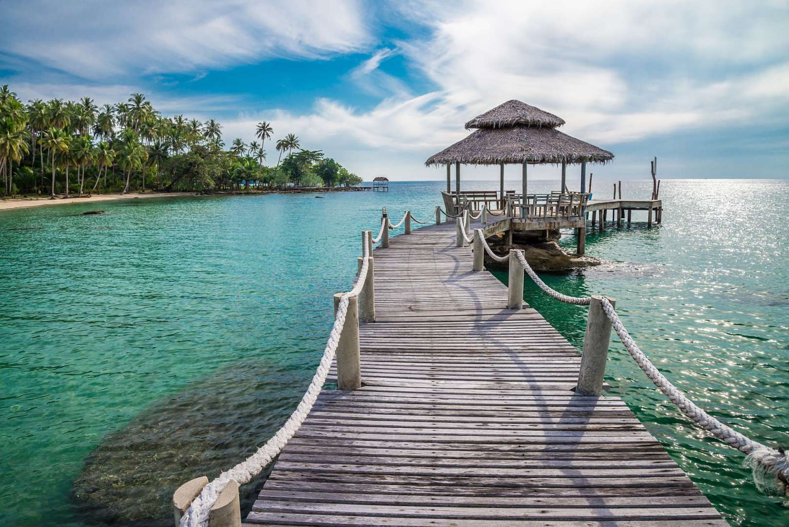 Ein Holzsteg führt zu einer kleinen Hütte im Ozean