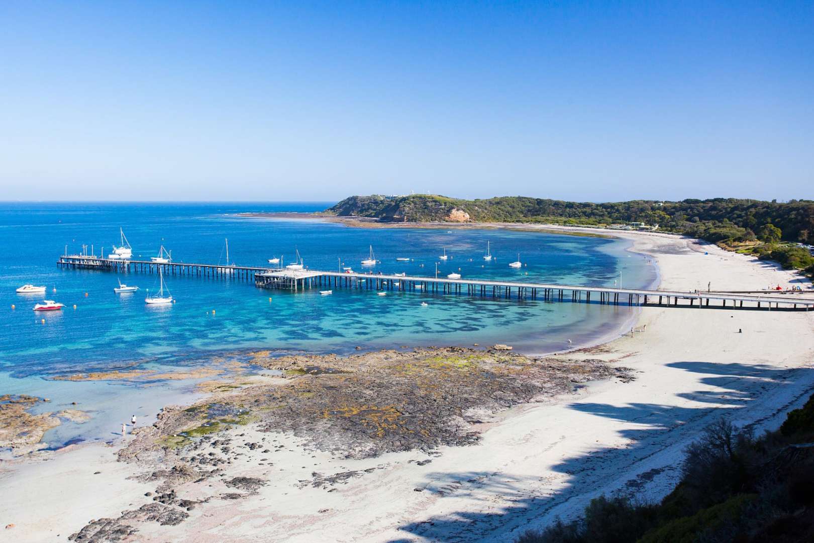 Ein Strand mit einem Pier und vielen Booten im Wasser