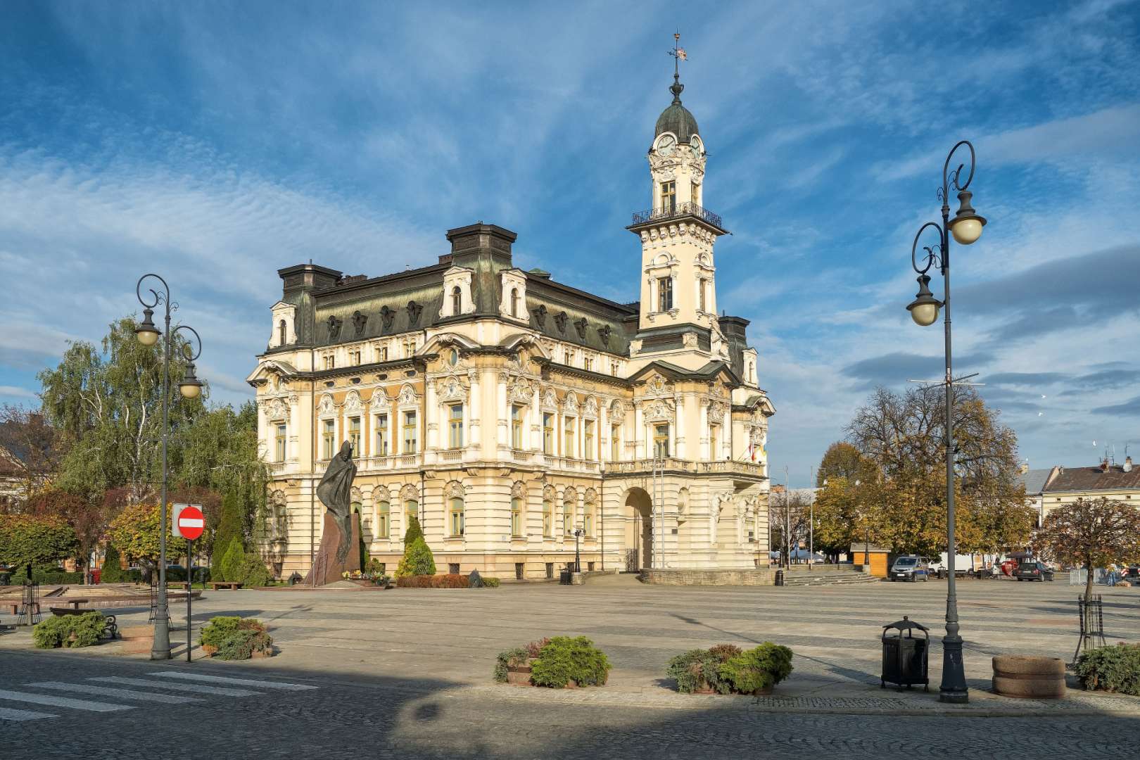 Ein großes Gebäude mit einem Uhrturm und einer Statue davor