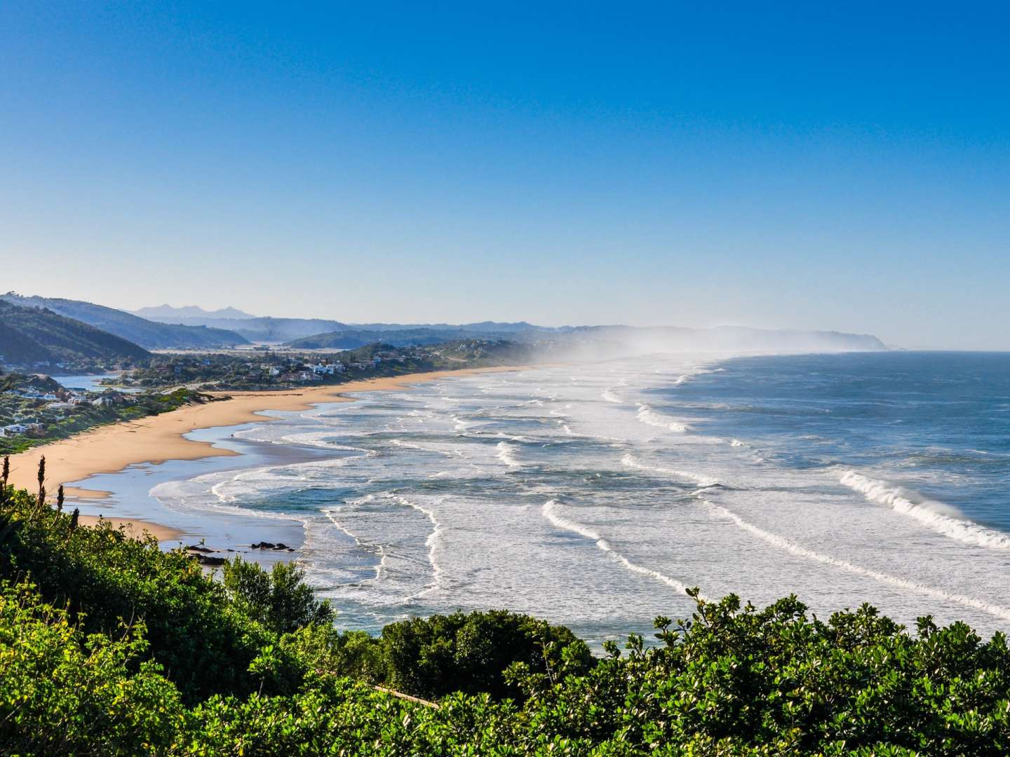 Ein Strand mit vielen Wellen und Bergen im Hintergrund