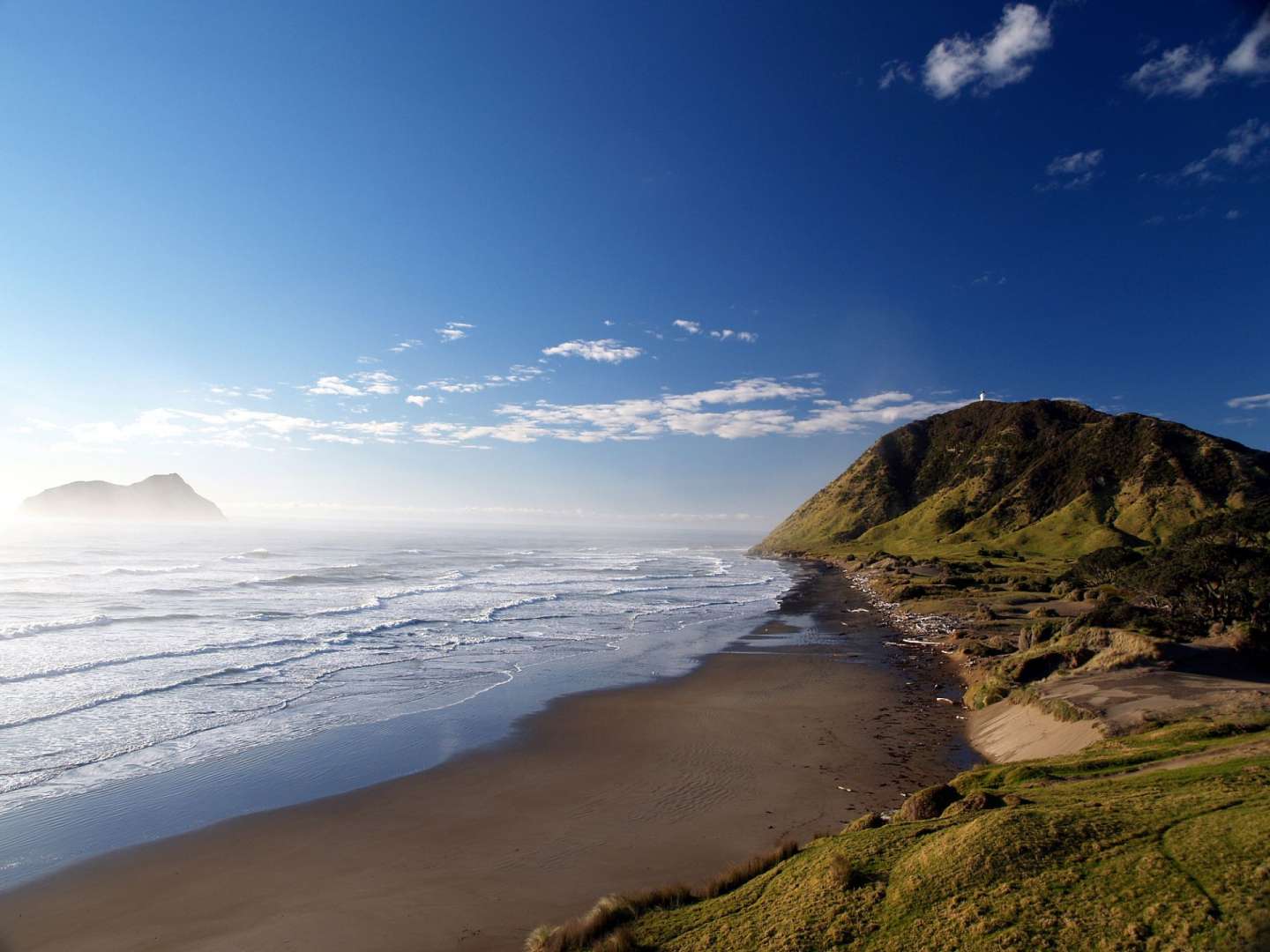Ein Strand mit einem Leuchtturm in der Ferne