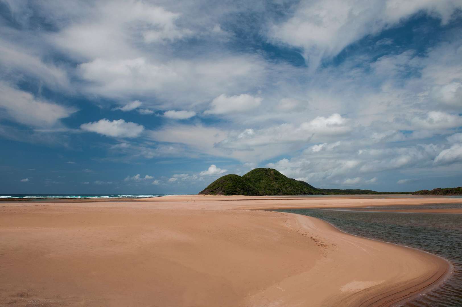 Ein Strand mit einem kleinen Hügel im Hintergrund