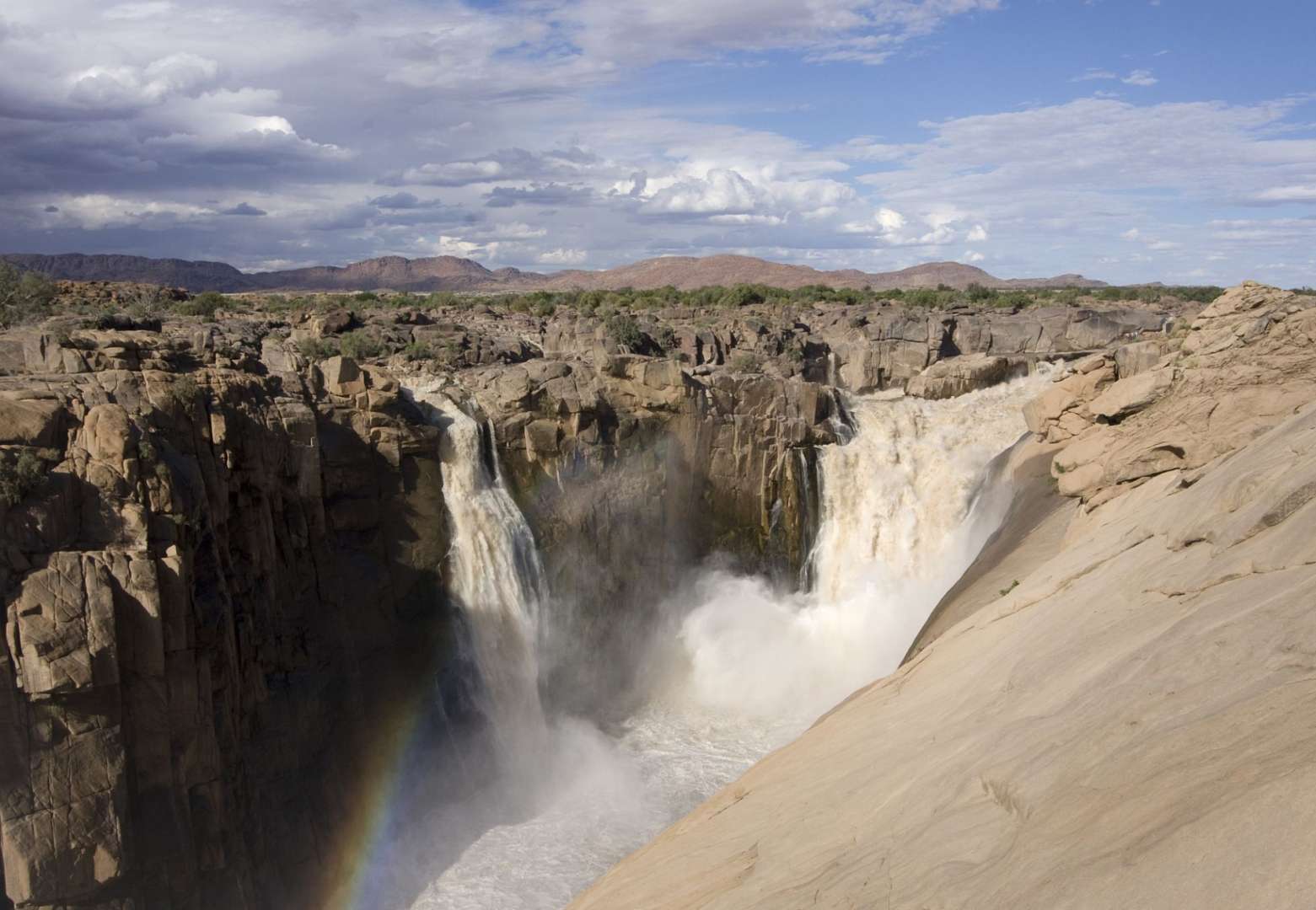 Ein Wasserfall mit einem Regenbogen im Hintergrund
