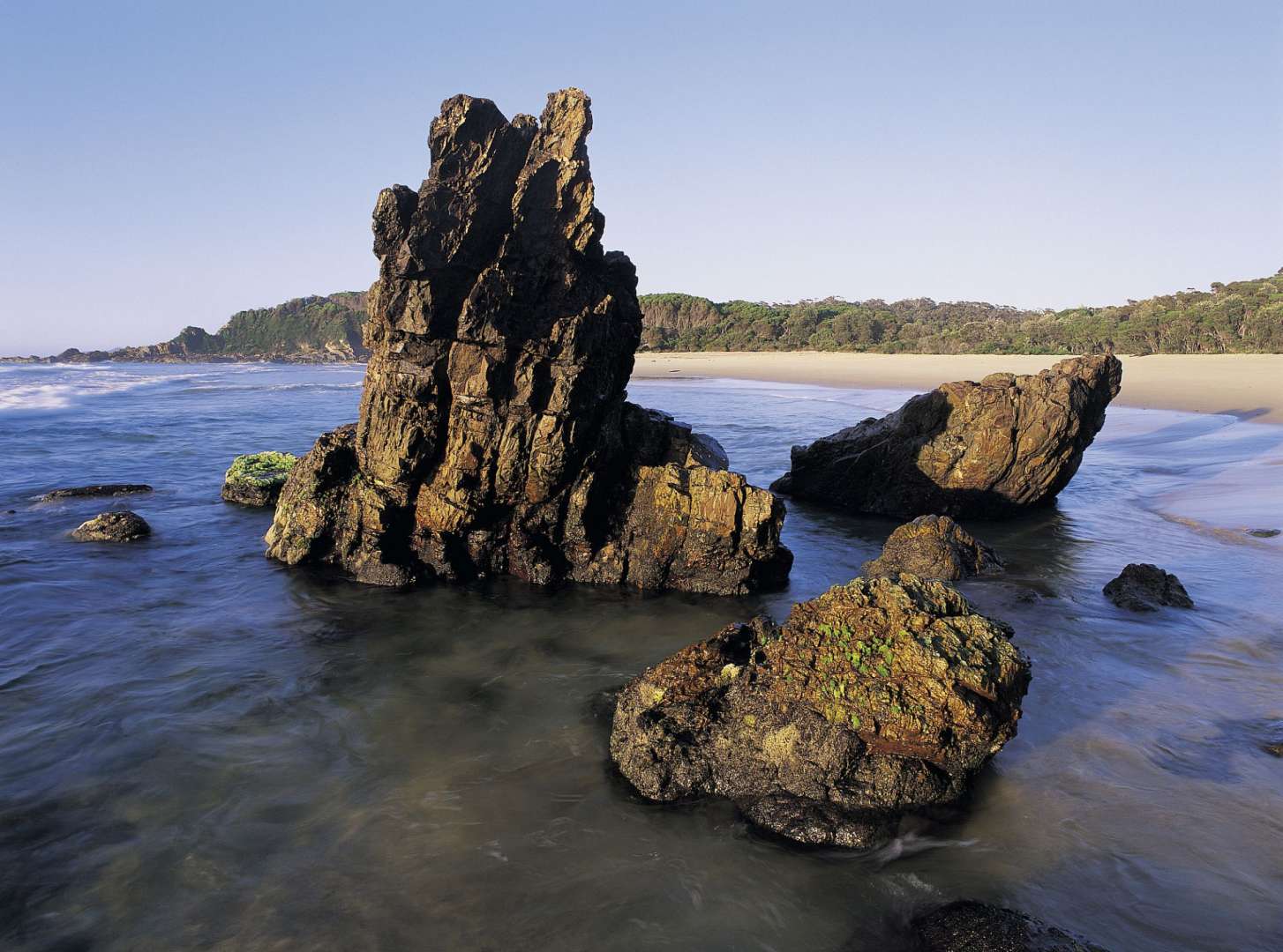 Ein großer Felsen sitzt in der Mitte eines Strandes