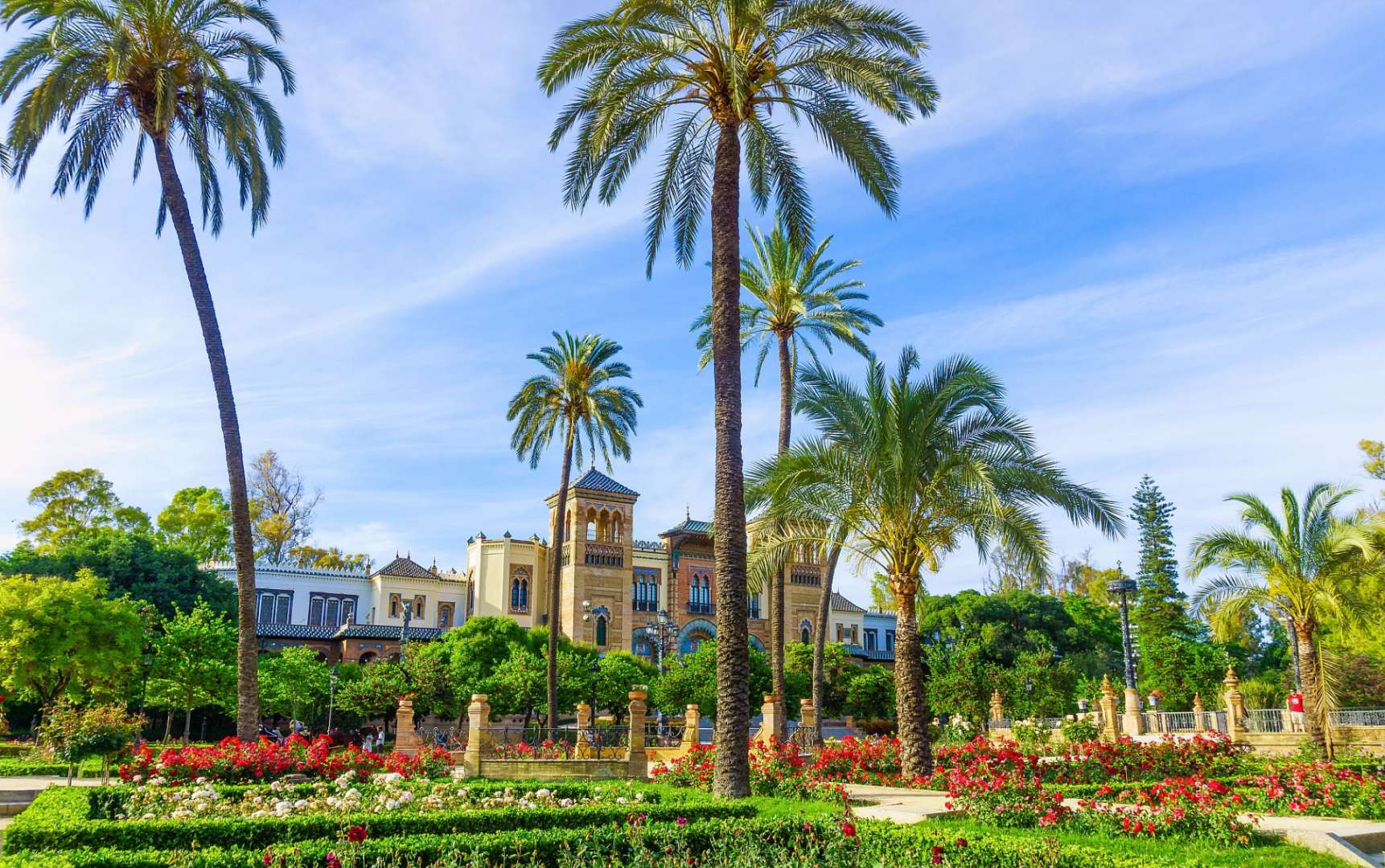 Ein Garten mit Palmen und Blumen vor einem großen Gebäude
