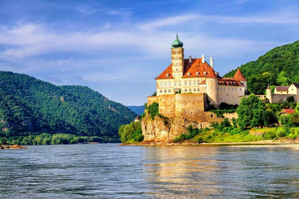 Ein Schloss sitzt auf einem Felsen über einem Fluss