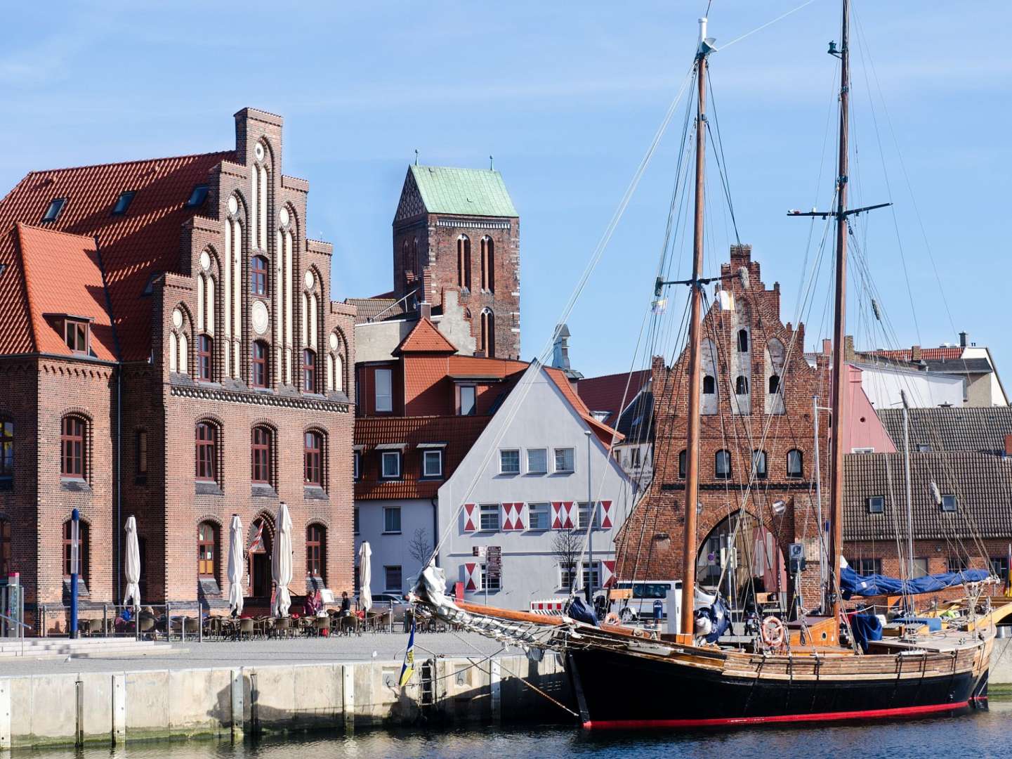 Ein Segelboot liegt in einem Hafen vor einem Backsteingebäude