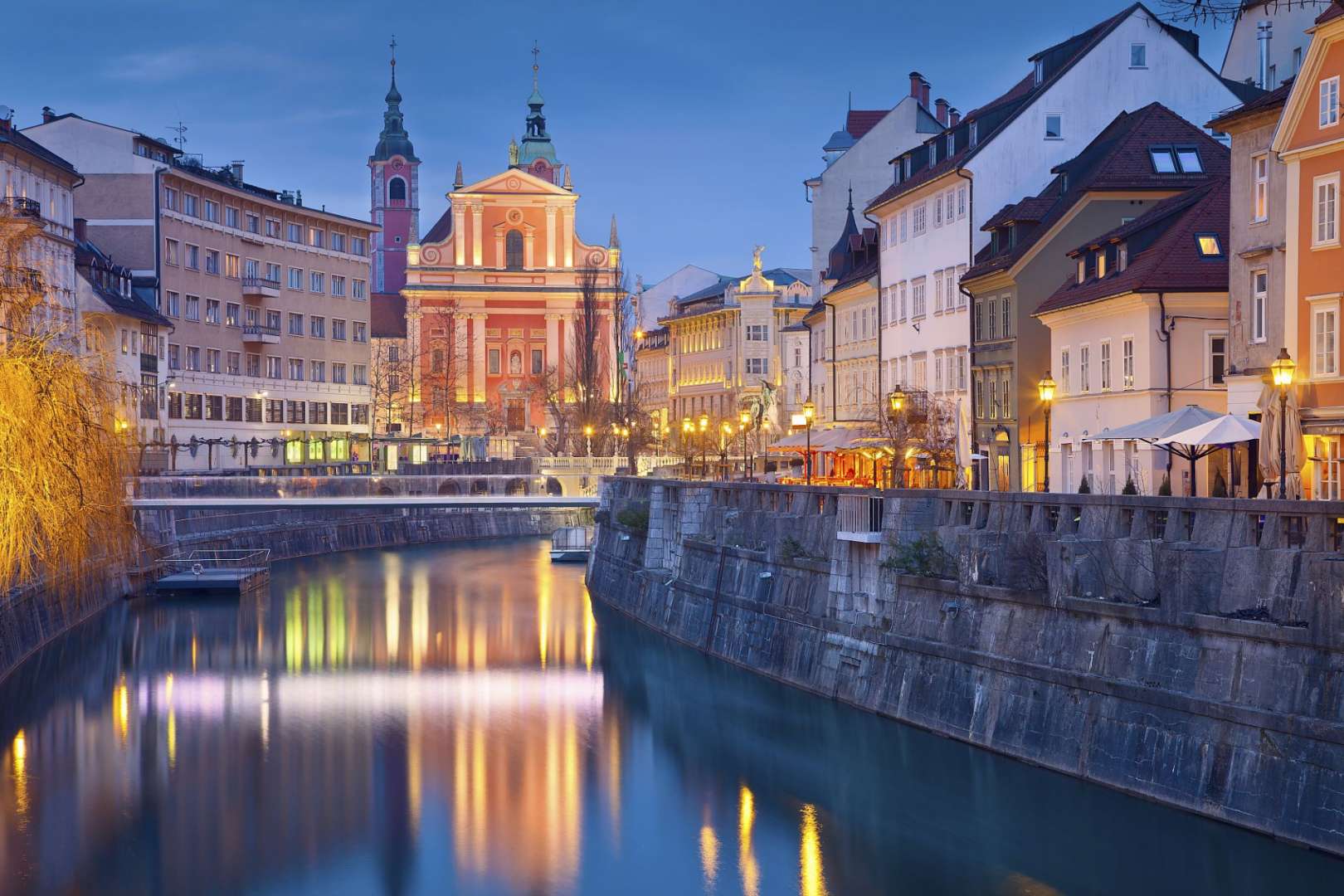 Eine Reihe von Gebäuden neben einem Fluss mit einer Kirche im Hintergrund