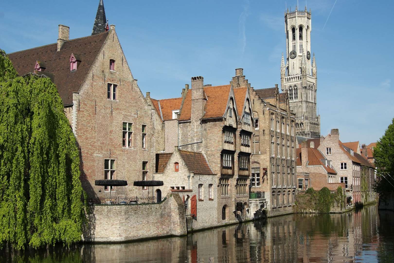 Eine Reihe von Gebäuden neben einem Fluss mit einem Turm dahinter