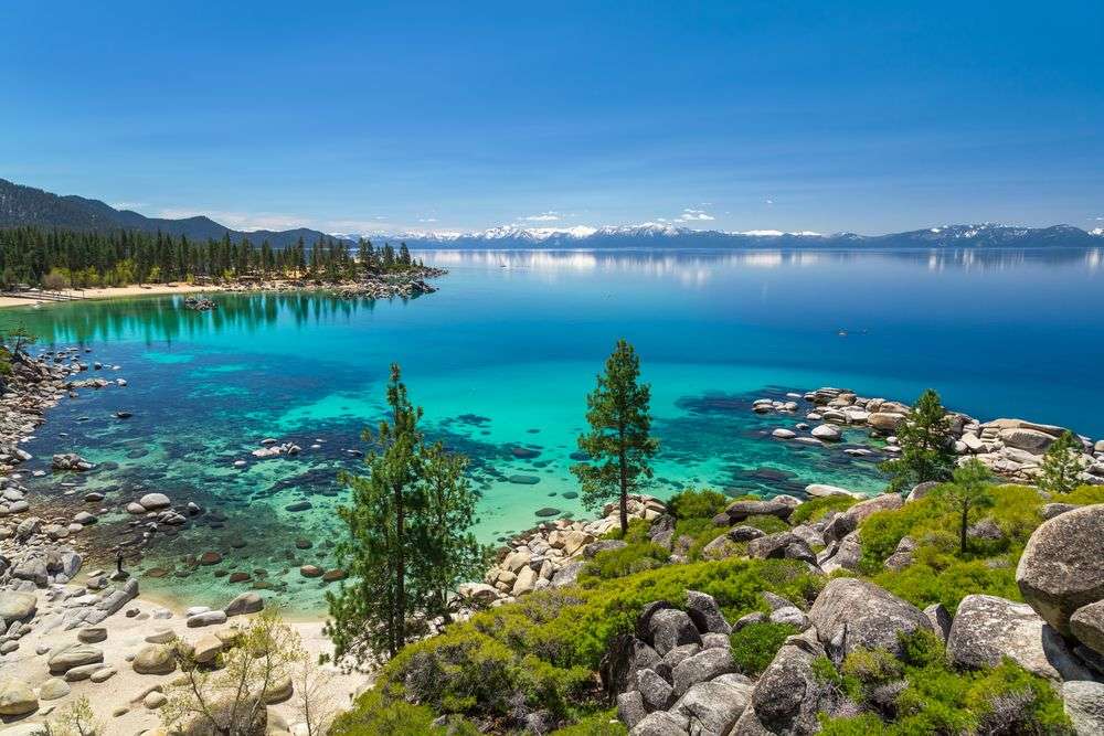 Ein See mit Bäumen und Felsen im Vordergrund