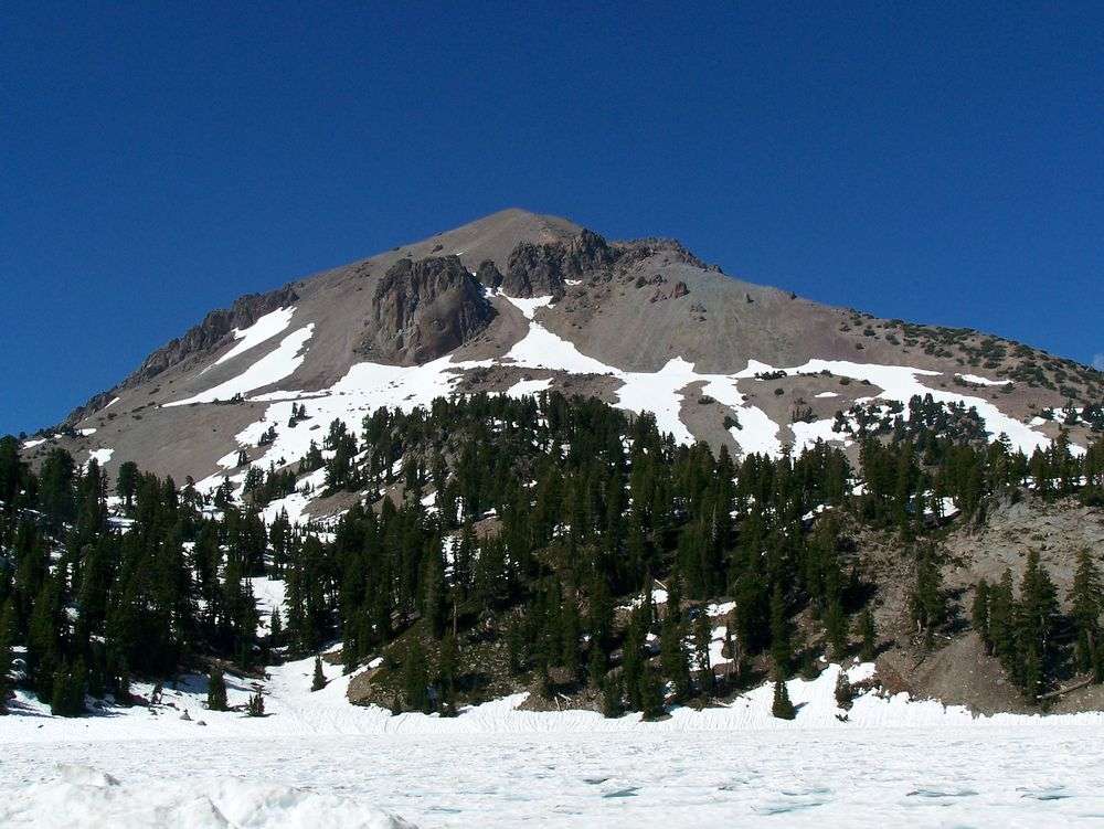 Ein schneebedeckter Berg mit Bäumen im Vordergrund