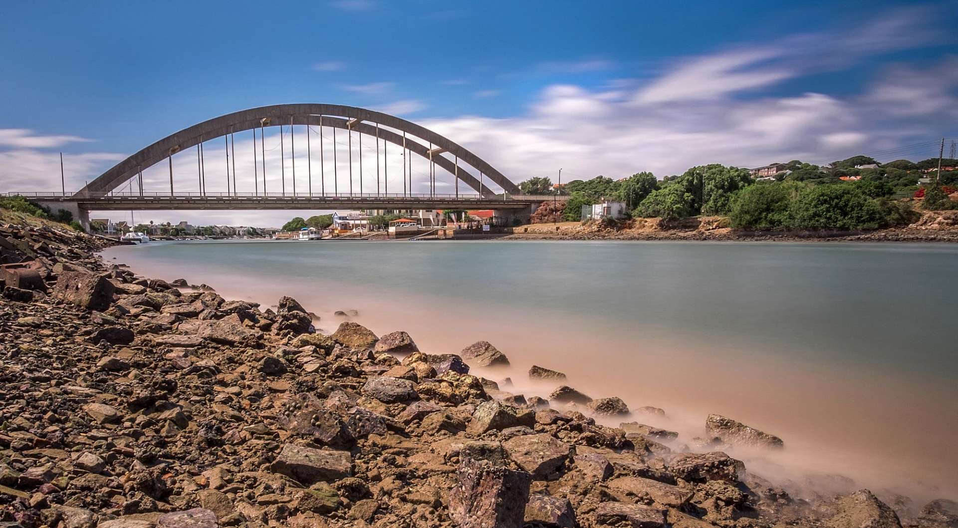 Eine Brücke über einen Fluss mit Felsen im Vordergrund