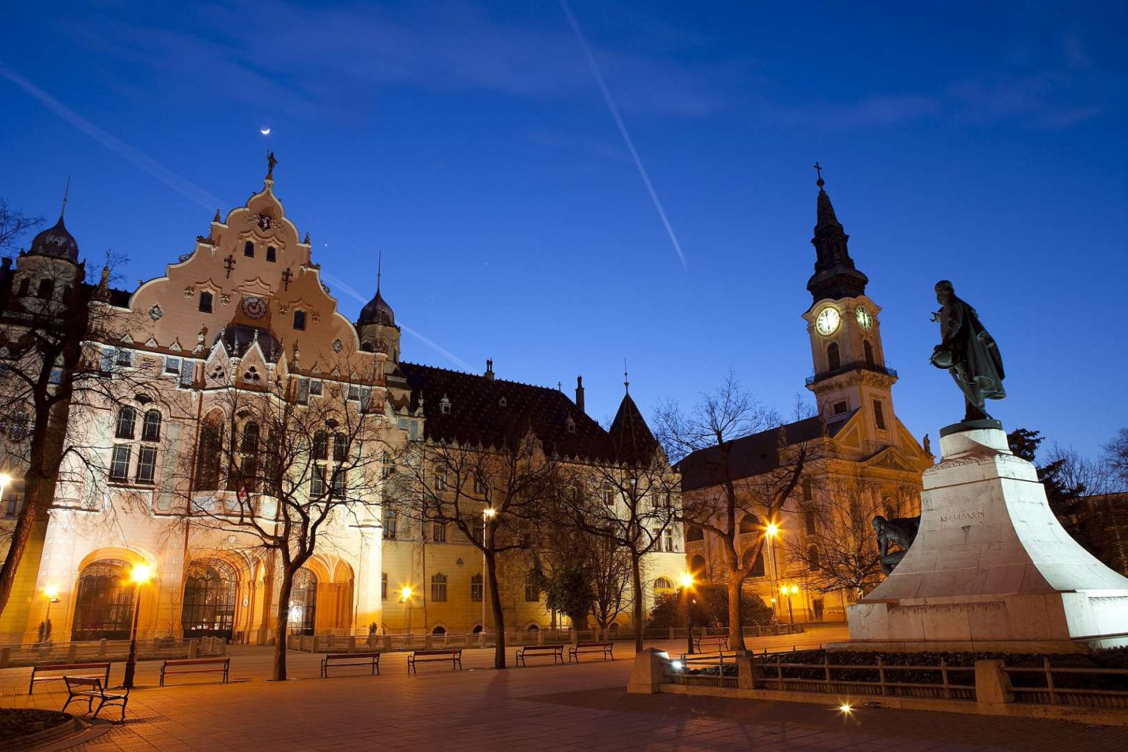Ein großes Gebäude mit einem Uhrturm und einer Statue davor