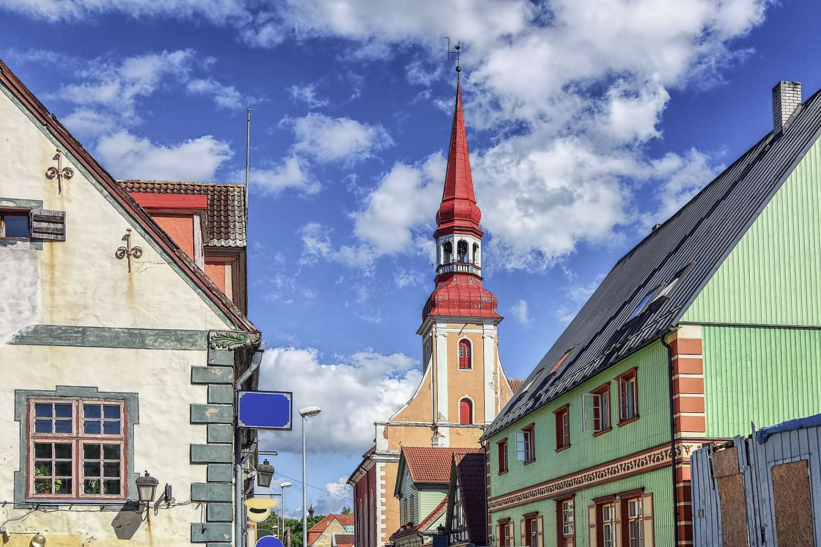 Eine Kirche mit einem roten Turm steht zwischen zwei Gebäuden