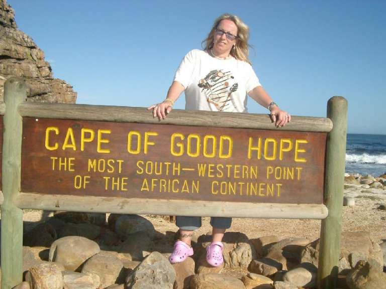 Eine Frau steht neben einem Schild mit der Aufschrift Cape of good hope