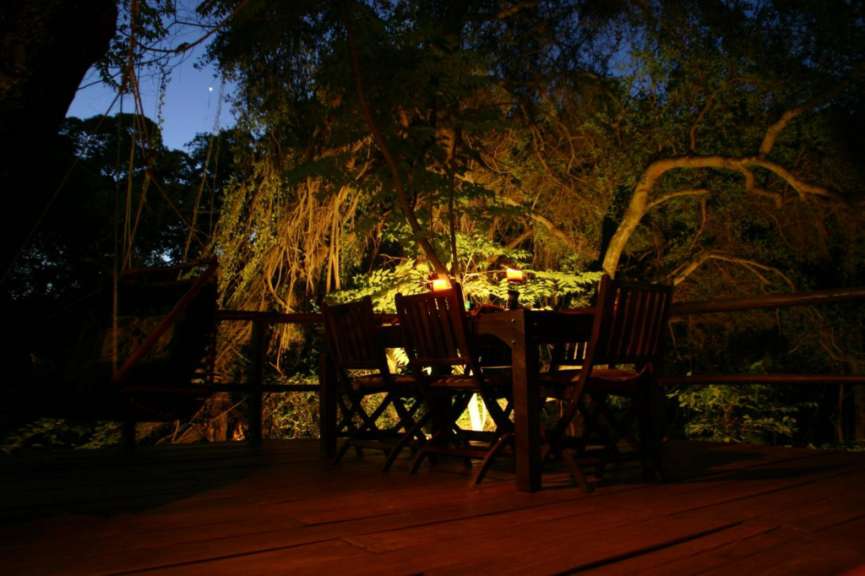 Ein Tisch und Stühle auf einem Holzdeck bei Nacht
