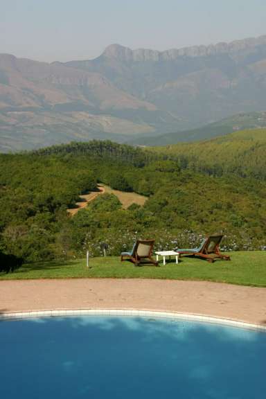 Liegestühle stehen neben einem Pool mit Blick auf die Berge