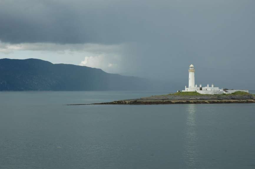 Ein Leuchtturm sitzt auf einer kleinen Insel im Ozean