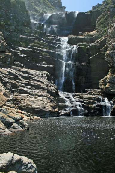 Ein Wasserfall stürzt von einer Klippe in einen Pool
