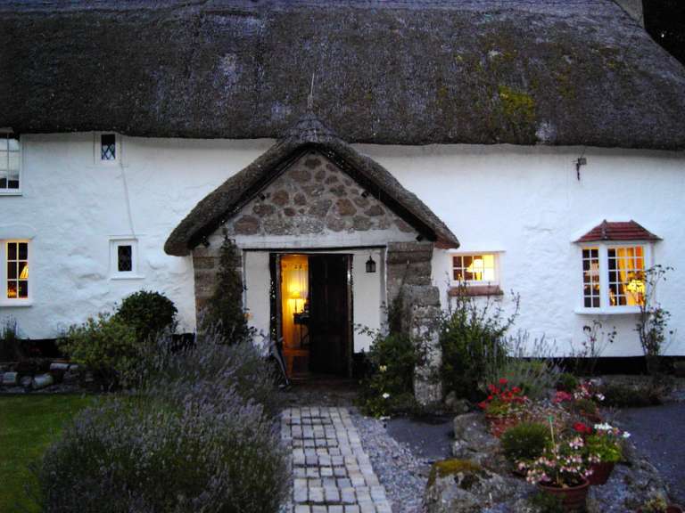 Ein strohdachgedecktes haus mit einem steinen eingang