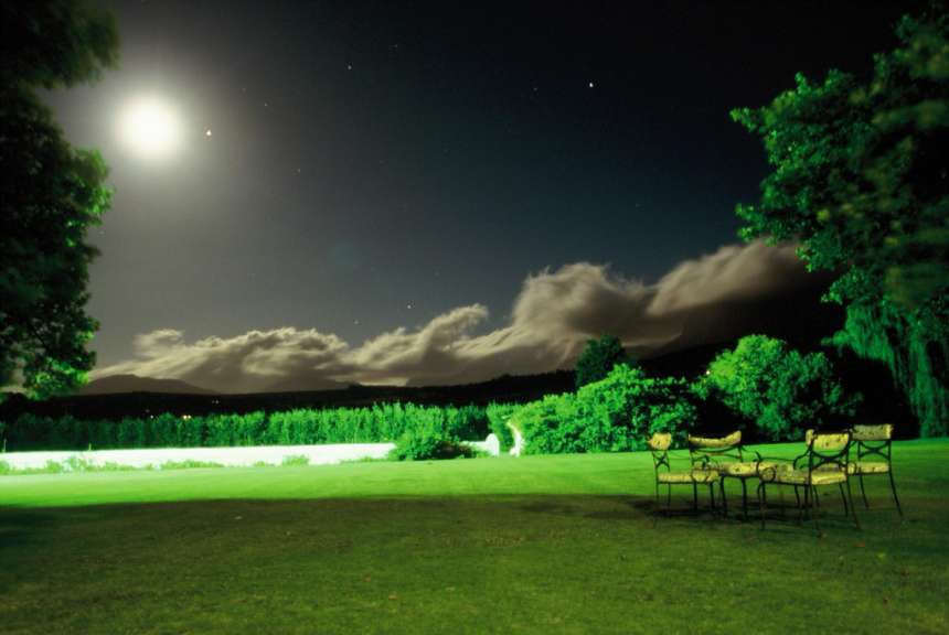 Ein Tisch und Stühle auf einem grünen Rasen bei Nacht