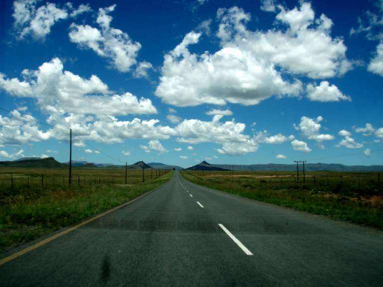 Eine Straße mit einem blauen Himmel und weißen Wolken dahinter