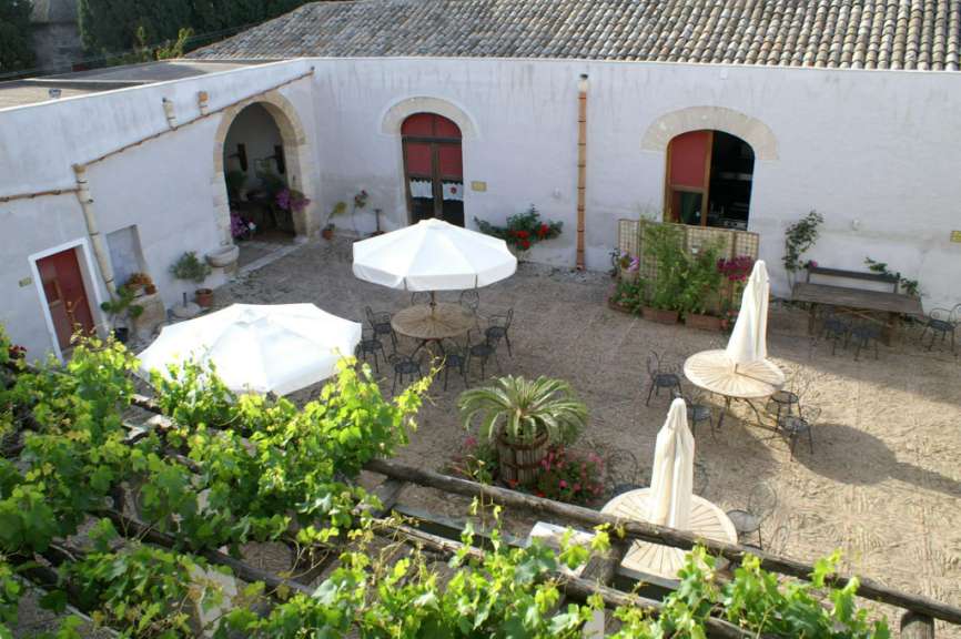 Ein kleiner Hof mit Tisch und Stühlen und weißen Sonnenschirmen