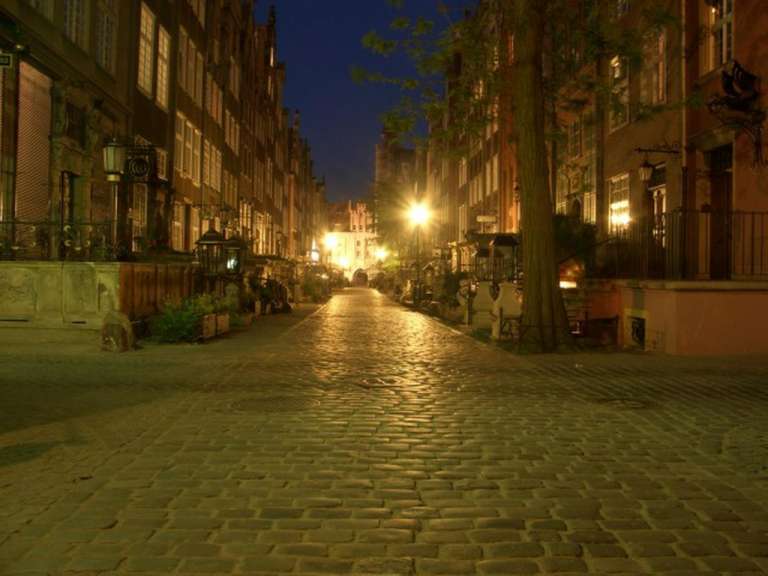 Eine gepflasterte Straße in einer Stadt mit einem Schild an der Seite, das sagt ' restauracja '