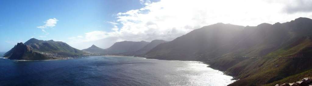 Die Sonne scheint durch die Wolken auf die Berge und das Meer