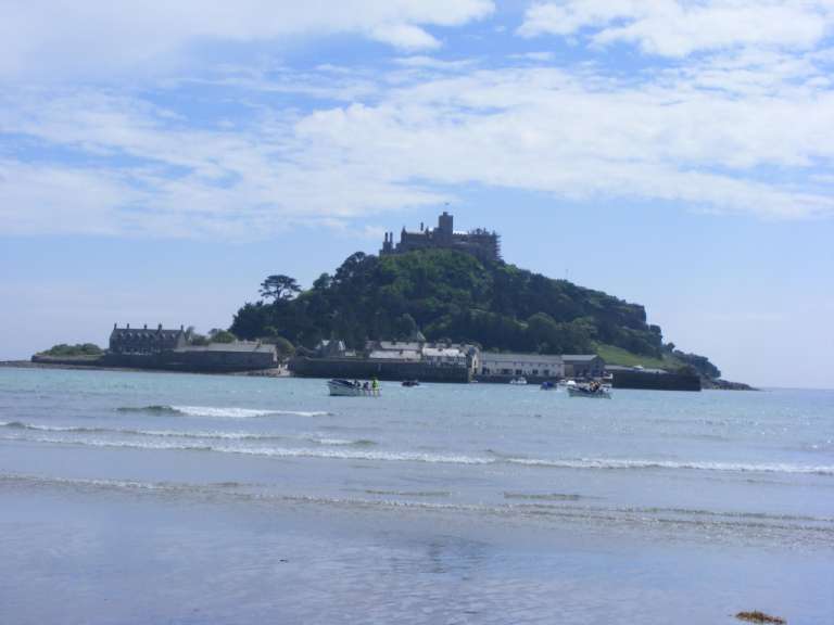 Ein Strand mit einem kleinen Boot im Vordergrund und einem großen Schloss im Hintergrund