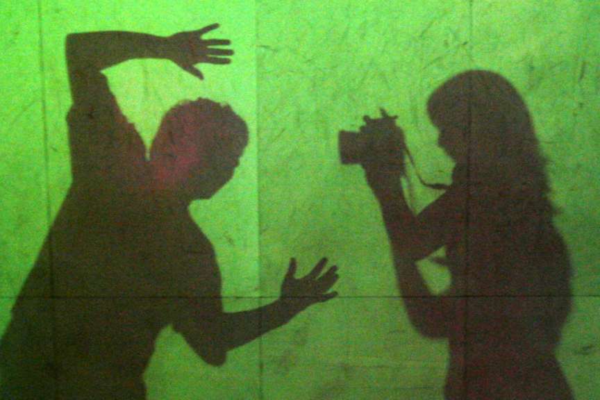 Ein Schatten eines Mannes und einer Frau auf einer grünen Wand