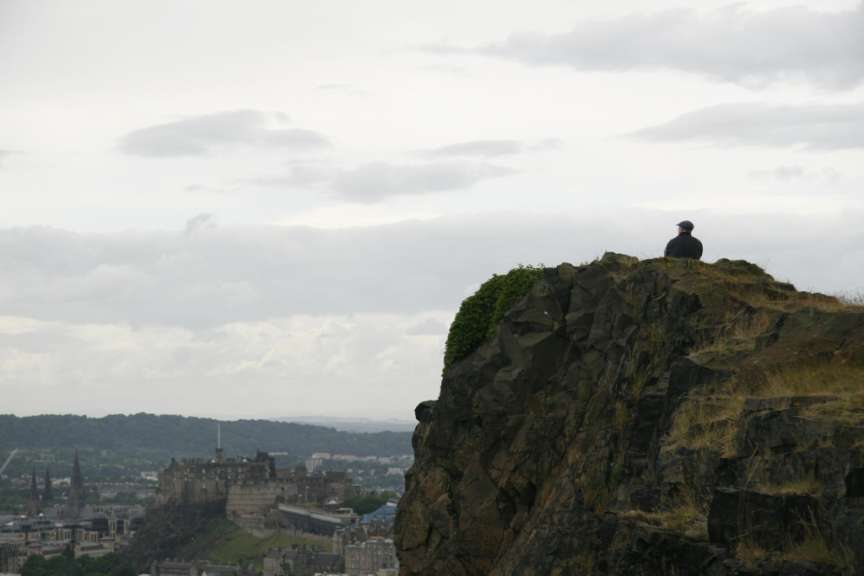 Ein Mann sitzt auf einem Felsen mit einem Schloss im Hintergrund