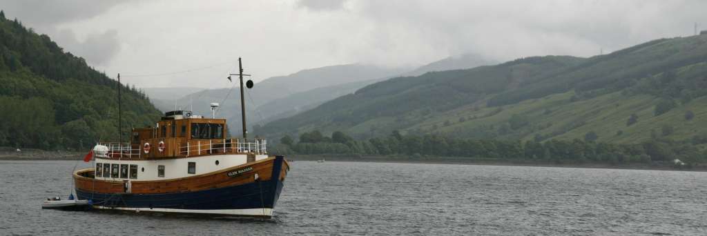 Ein blau-weißes Boot mit der Aufschrift " loch ness " schwimmt auf einem See