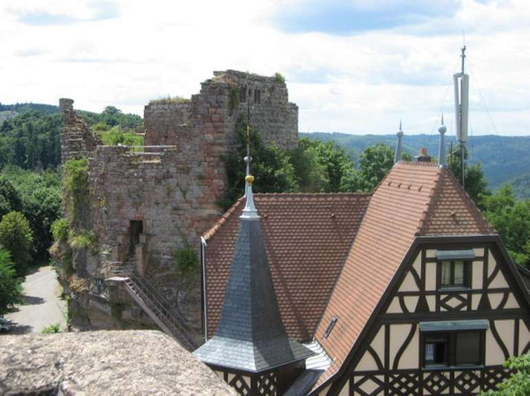 Ein Gebäude mit einem Turm auf dem Dach steht neben einer Burgruine