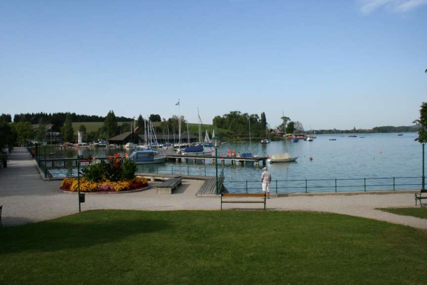 Ein Mann steht auf einer Bank neben einem See mit vielen Booten darauf