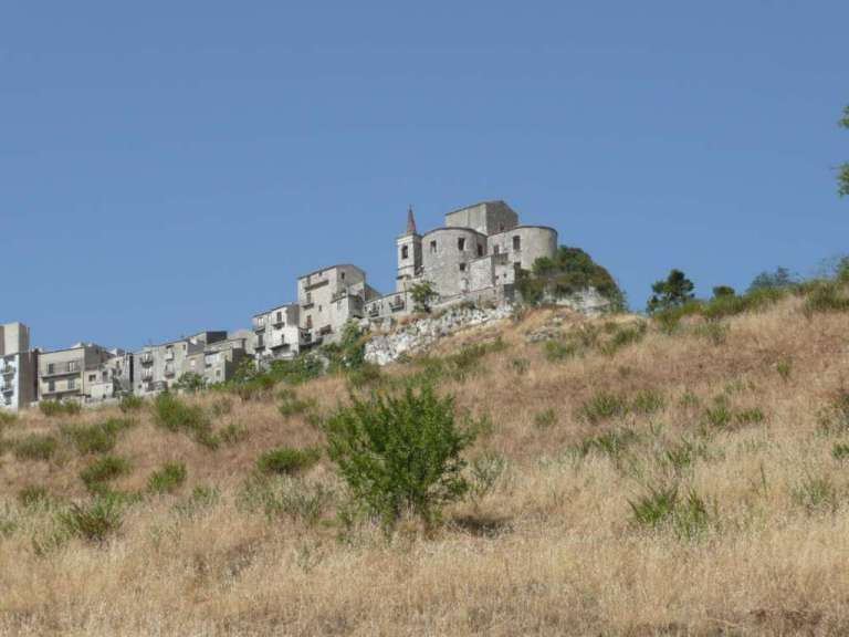 Ein kleines Dorf auf einem Hügel mit einem großen Gebäude im Hintergrund