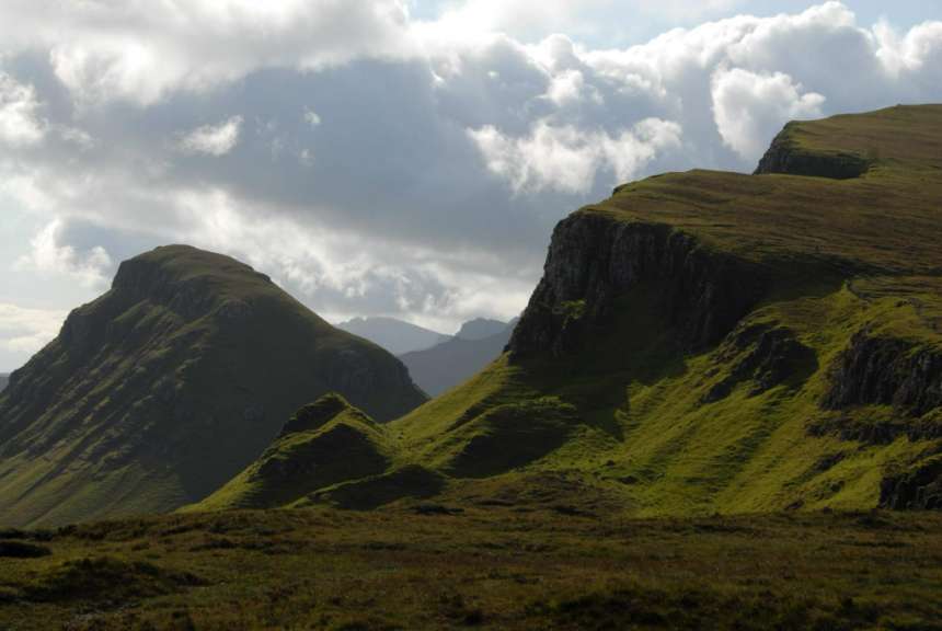 Ein grüner Berg mit einem bewölkten Himmel im Hintergrund