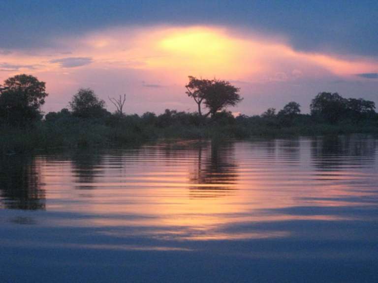 Ein Sonnenuntergang über einem Fluss mit Bäumen im Vordergrund