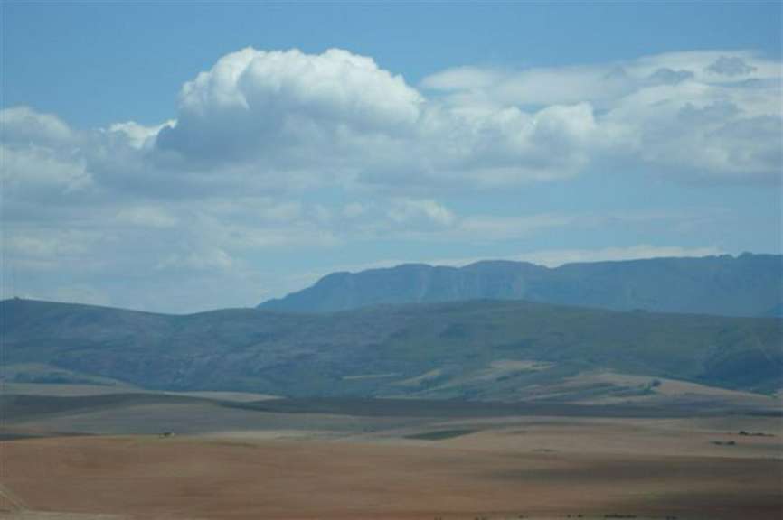 Ein bewölkter Himmel über einem Feld mit Bergen im Hintergrund