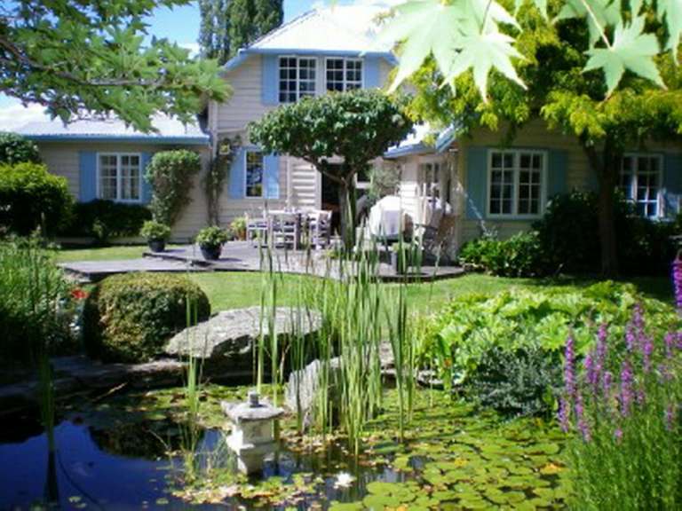 Ein Garten mit einem Teich und einem Haus im Hintergrund