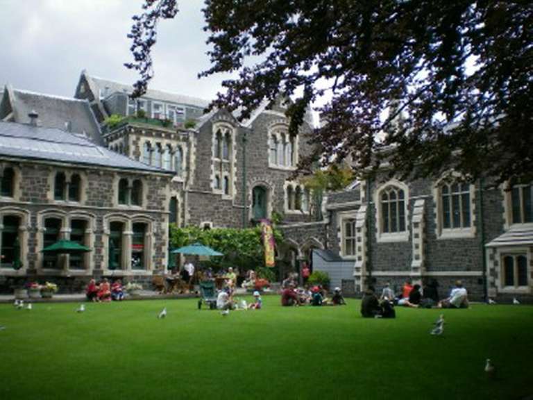 Eine Gruppe von Menschen sitzt auf dem Rasen vor einem großen Gebäude