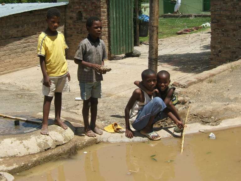 Eine Gruppe von Kindern steht neben einem schlammigen Fluss