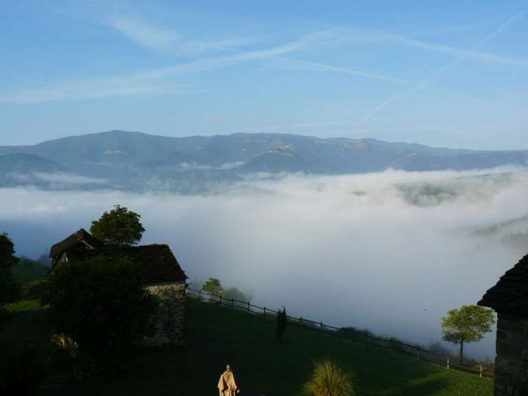 Eine Statue steht auf einem Hügel mit Blick auf eine neblige Landschaft