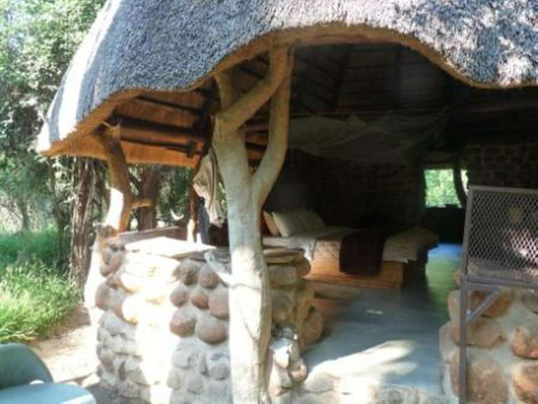Eine Steinhütte mit Strohdach und Betten darunter .