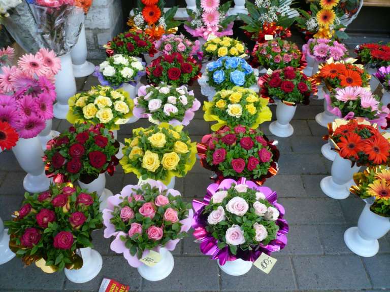 Bunte Blumen in weißen Vasen auf einem Bürgersteig