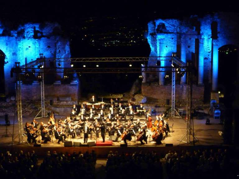 Ein Orchester spielt auf einer Bühne mit blauen Lichtern