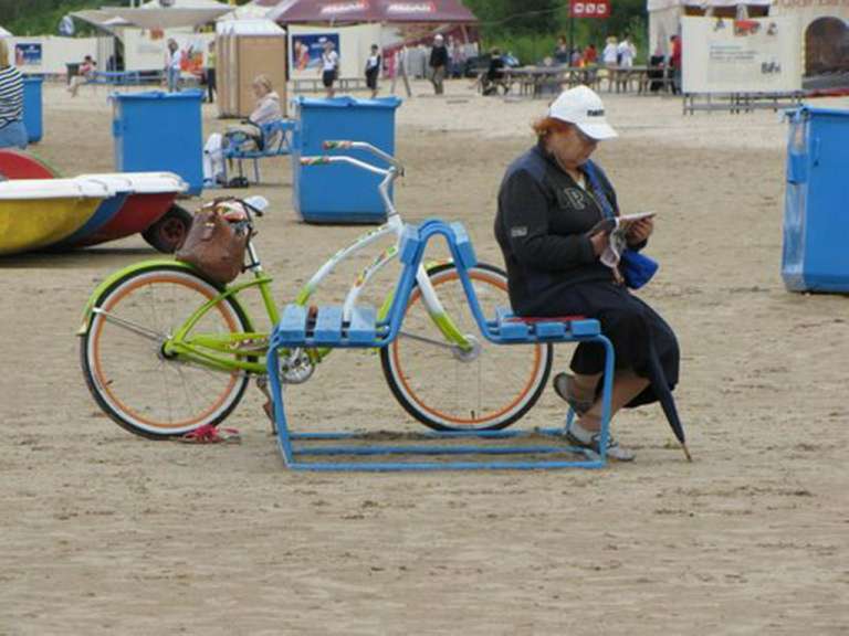 Eine Frau sitzt auf einem Stuhl neben einem Fahrrad und liest ein Buch