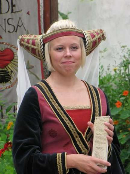 Eine Frau in einem roten und schwarzen Kleid hält ein Buch in der Hand